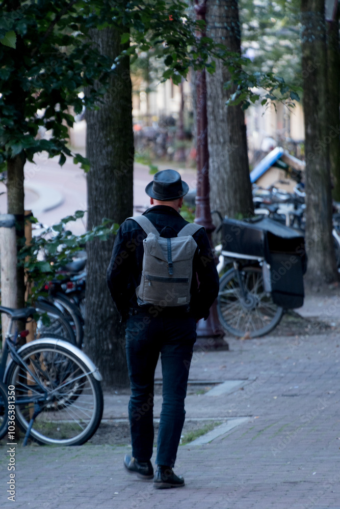 Man in black jeans and leather fedora walking away on a street in Binnenstad Man in black jeans and leather fedora walking away on a street in Binnenstad
