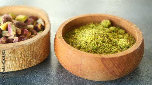 Wooden bowl filled with pistachios and powder on a table 