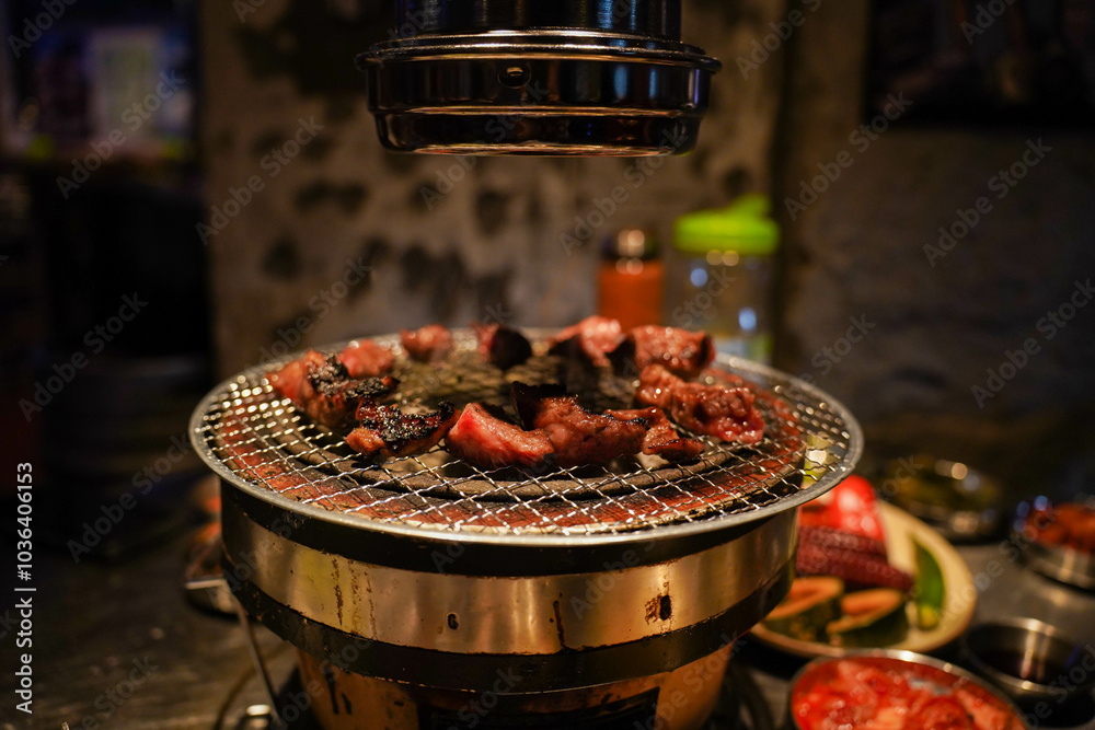 Grilled meat on a charcoal grill pan at Korean BBQ restaurant.