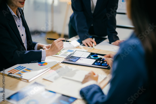 Business people having a meeting, analyzing financial charts and graphs using digital tablet and document, brainstorming and discussing about new business project