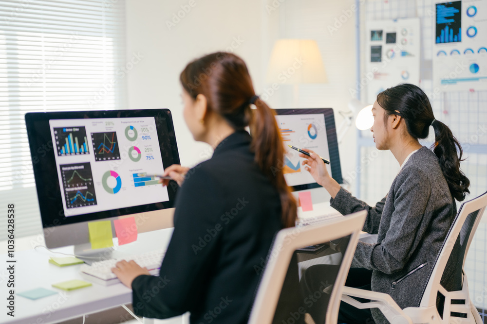Two asian businesswomen collaborate in a bright office, analyzing data and planning for their startup's growth Two asian businesswomen collaborate in a bright office, analyzing data and planning for their startup's growth