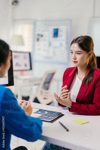 Two businesswomen discussing a detailed report in a bright office, showcasing teamwork and planning skills for success