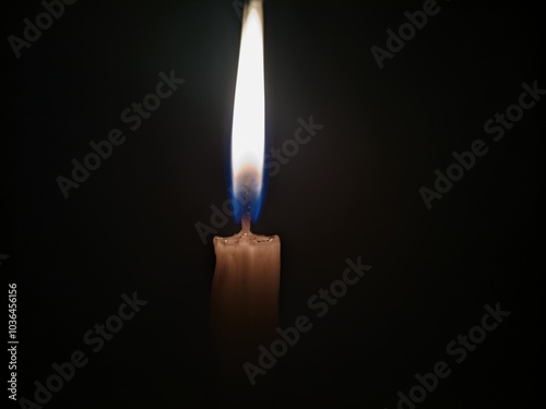 A single unlit candle stands tall against a pitch black background The candle is white with a slightly yellow hue  and its wick is long and straight The image is simple yet striking with the candles