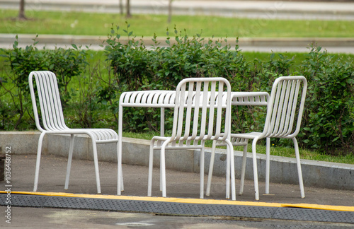 A white metal table with four chairs is sitting on a sidewalk