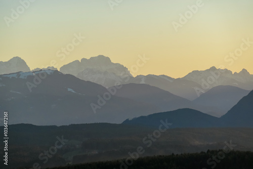 Scenic sunset view of majestic mountain peak Jof Montasio in Julian Alps seen from Sternberg, Wernberg, Carinthia, Austria. Valley covered by idyllic forest in Austrian Alps. Tranquil alpine landscape photo