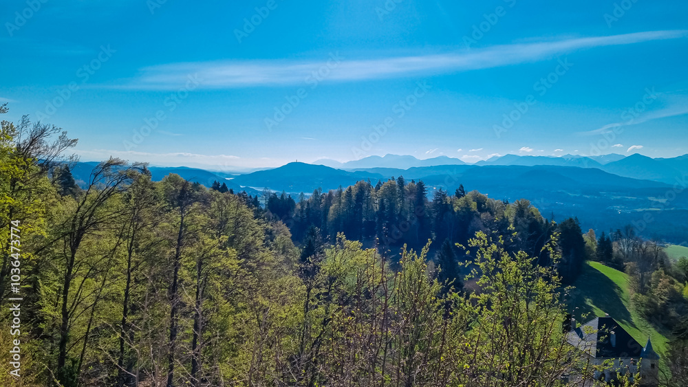 Panoramic view of idyllic Rosental valley seen from Sternberg in Wernberg, Carinthia, Austria. Looking atmajestic wooden tower Pyramidenkogel, Woerthersee, Karawanks and Julian Alps. Alpine landscape