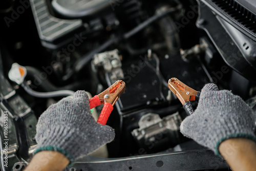 Top view of black and red jumper cables in male hand for charging broken car battery. photo