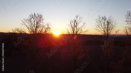 Beautiful sun rises over trees forest on the hill during fall autumn