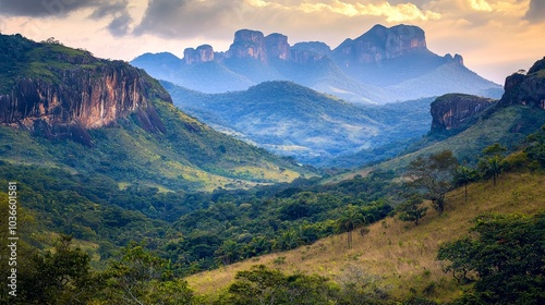 Panoramic view of a mountain range with lush vegetation and dramatic rock formations in the distance, under a cloudy sky.