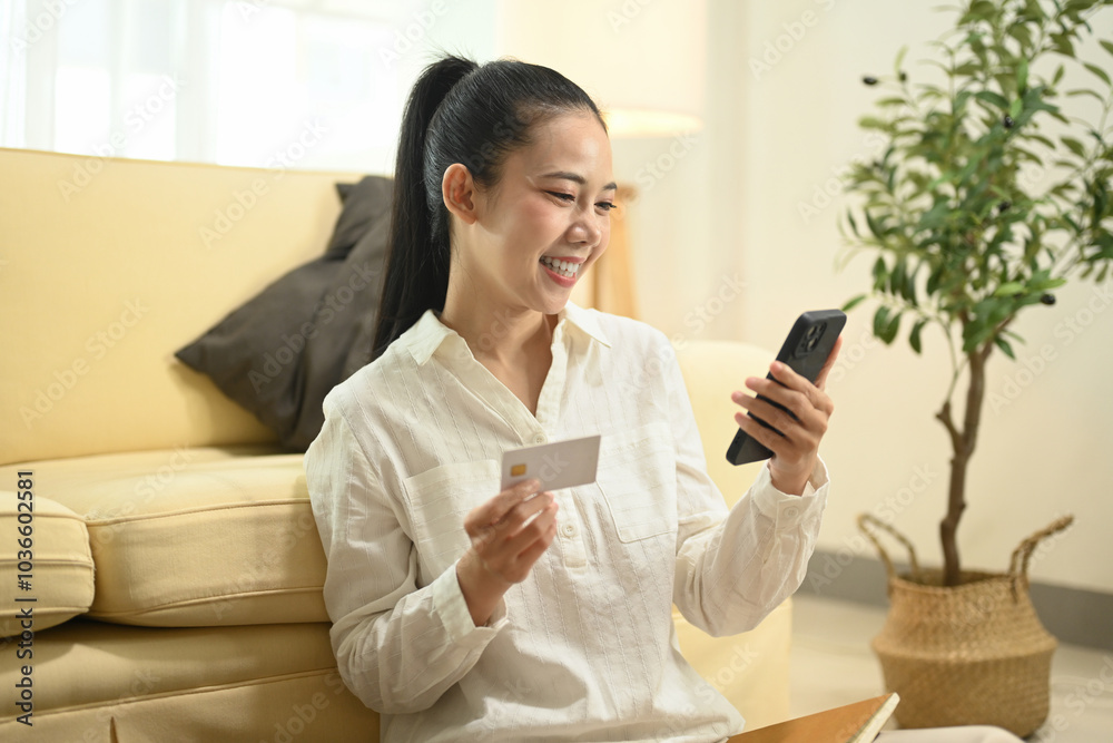 Satisfied young asian woman holding a credit card and using mobile phone for online shopping Satisfied young asian woman holding a credit card and using mobile phone for online shopping