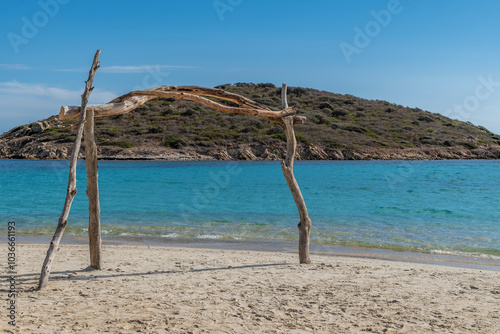 A frame made of wooden logs on the beach of Tuerredda, Sardinia, Italy and the Tuaredda island in the background photo