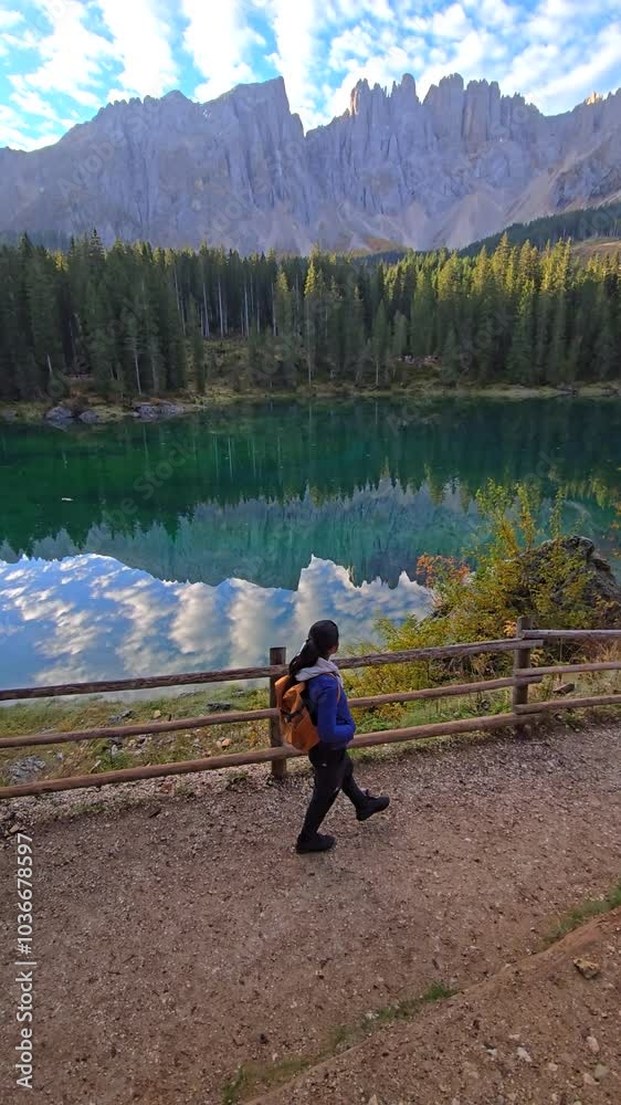 Stroll along a scenic path beside a shimmering lake, framed by majestic mountains and vibrant autumn foliage. Karersee lake in the Dolomites, South Tyrol, Italy, also known as lake Carezza Stroll along a scenic path beside a shimmering lake, framed by majestic mountains and vibrant autumn foliage. Karersee lake in the Dolomites, South Tyrol, Italy, also known as lake Carezza