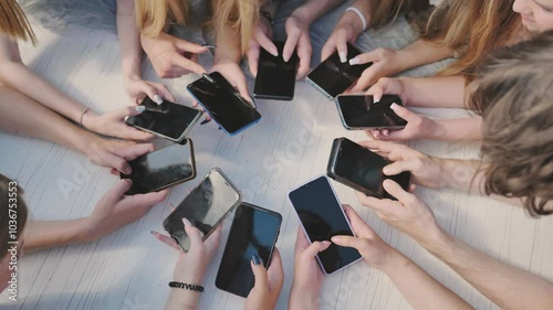 People holding their smartphones around a white table, using their devices and showing a sense of community.