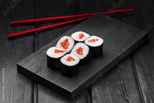 Japanese rolls, maki sushi with tomato on black wooden background. photo
