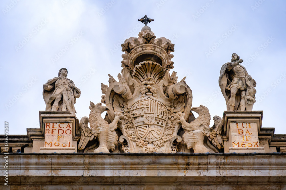 Ancient stone coat of arms and sculptures atop the Royal Palace, Madrid, Spain. Ancient stone coat of arms and sculptures atop the Royal Palace, Madrid, Spain.