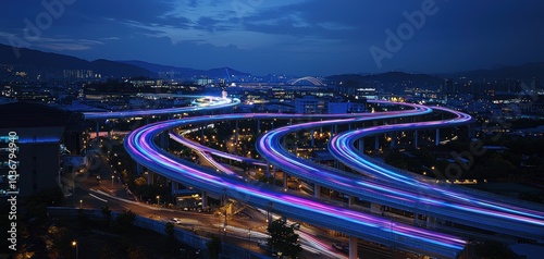 Winding highway illuminated at night with vibrant lights and cityscape in background.