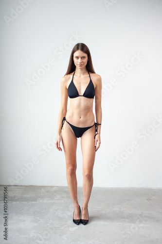 Confidence always completes your look. Studio portrait of an attractive young woman posing in a bikini against a grey background. photo