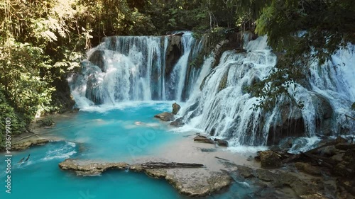 Amazing cascade waterfalls with clear blue water and wooden bridge in Central Sulawesi, drone view