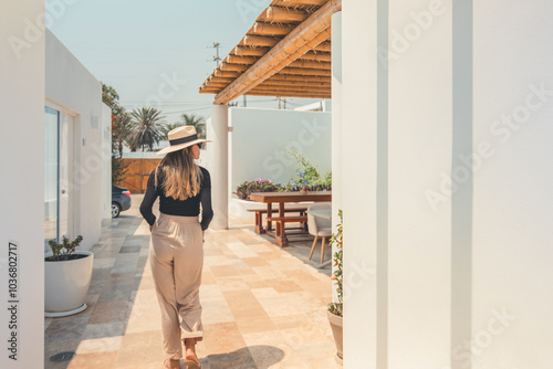 A woman wearing a straw hat walks down a hallway