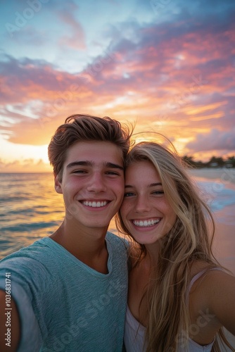 A young couple taking a romantic selfie at sunset on the beach, with the colorful sky and ocean waves behind them, both smiling and embracing