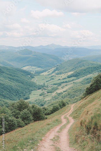 A scenic view of a winding trail through lush green hills under a blue sky.