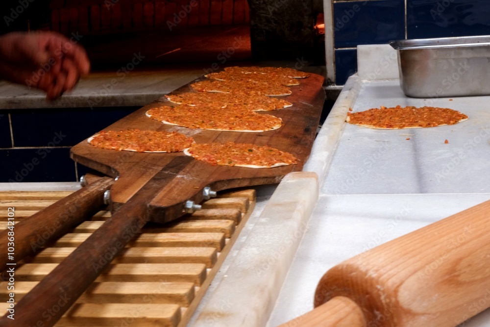 Delicious lahmacun, a Turkish culinary delight, is placed on the oven rack to be cooked. Traditional Turkish cuisine. Ready food industry. Delicious lahmacun, a Turkish culinary delight, is placed on the oven rack to be cooked. Traditional Turkish cuisine. Ready food industry.