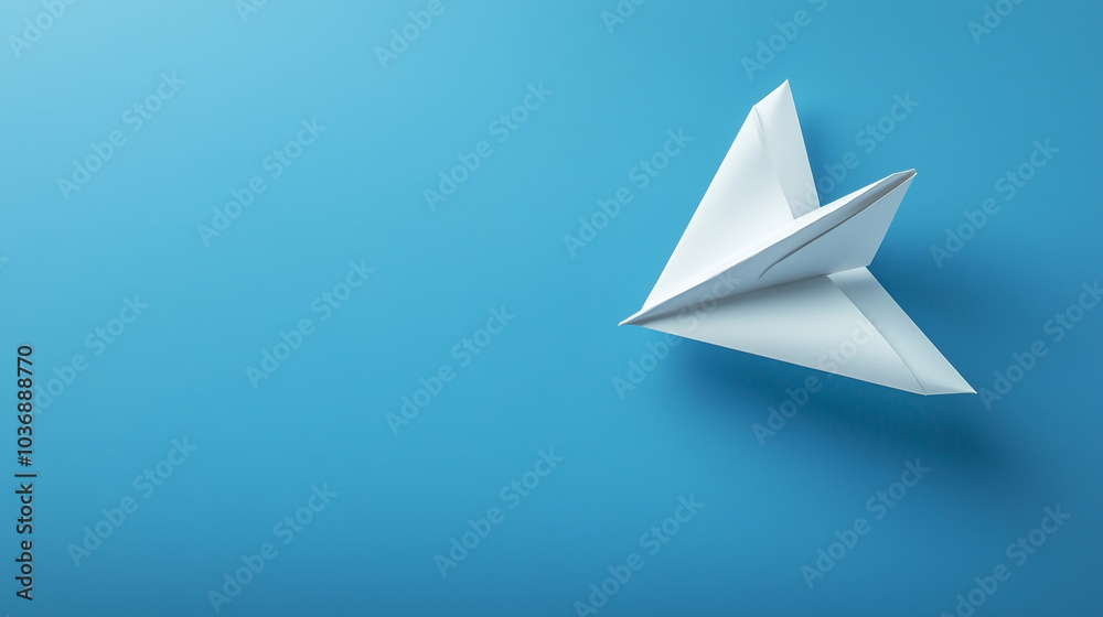 Fototapeta premium A paper airplane, crafted from white paper, soars gracefully in a bright blue space, symbolizing imagination, play, and childhood creativity.