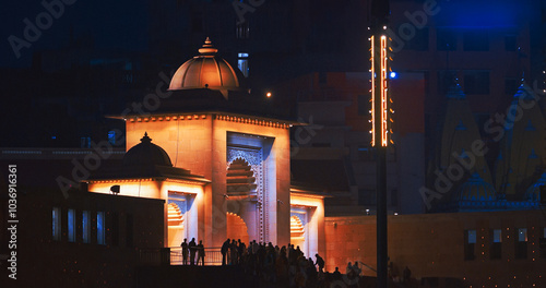 Varanasi, Uttar Pradesh, India. People walking on Lalita Ghat near Kashi Vishwanath Temple complex. Cinematic Camera movement moving along riverbank embankment. View from riverside. night lights