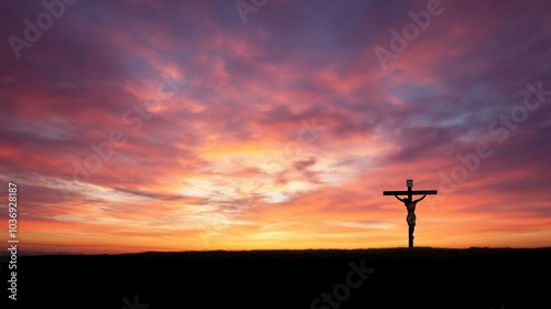 A silhouetted figure on a cross against a vibrant sunset backdrop.