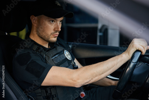 Serious patrolman driving car monitoring order on street closeup portrait shot