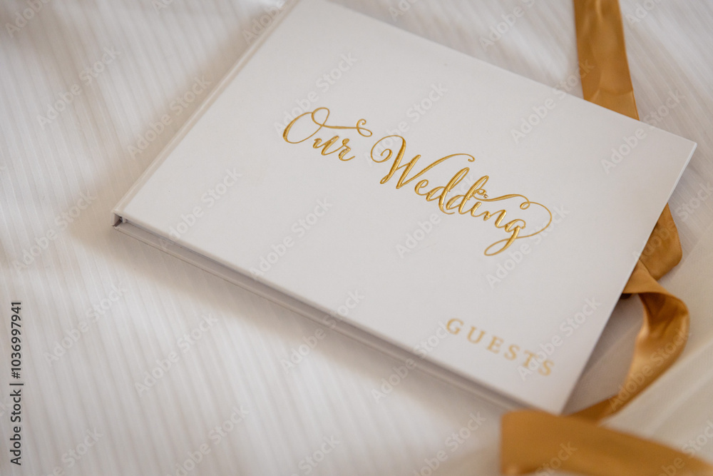 Elegant wedding guest book with gold lettering on a white cover. Perfect for capturing memories and heartfelt messages at weddings. Ideal accessory for couples cherishing their special day