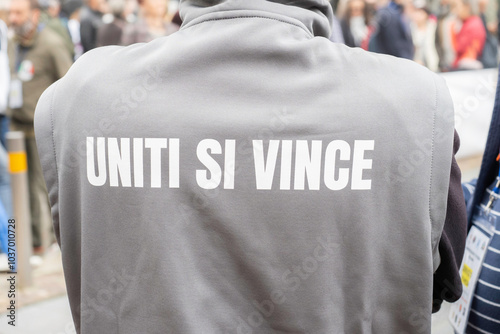 Una persona di spalle durante una manifestazione esibisce la scritta UNITI SI VINCE