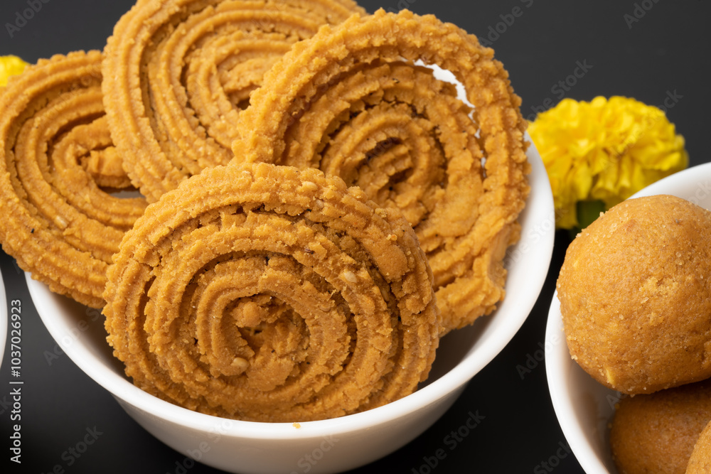 Crunchy fried homemade Chakli in a plate. Chakli is a savory snack from India made out of rice, mixed yellow and green lentils along with spices Diwali Crunchy fried homemade Chakli in a plate. Chakli is a savory snack from India made out of rice, mixed yellow and green lentils along with spices Diwali