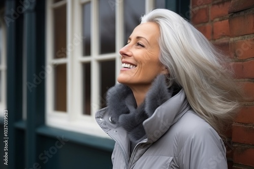 Portrait of a happy mature woman smiling outdoors, wearing warm clothing