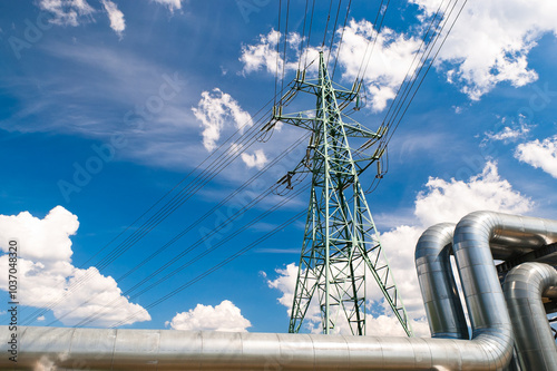 close up of pipeline and power line, blue sky and clouds in the background
