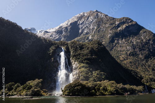Waterfall cascading down mountain into milford sound, new zealand