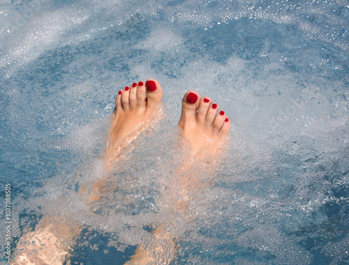 Tableau sur toile well-groomed female feet with red toenail polish soaking in the tub during a rel