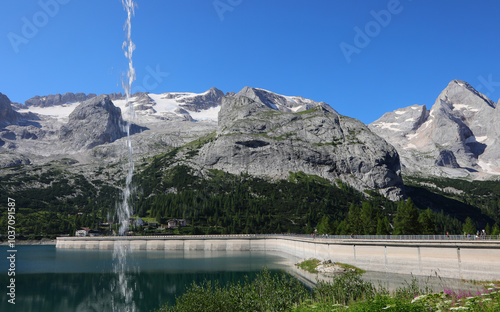 Waterfall and the glacier shrinking on marmolada mountain in the alps showing the impact of global warming photo