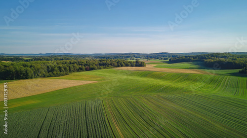 Scenic aerial view of rolling green hills and farmlands under a clear blue sky