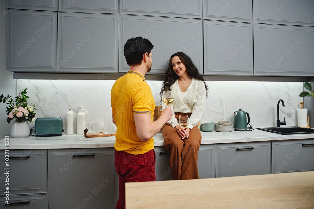 Couple enjoying a relaxing evening with drinks in a stylish modern kitchen Couple enjoying a relaxing evening with drinks in a stylish modern kitchen