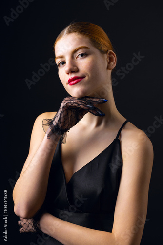 A young redhear girl with clean skin wearing black gloves. Beauty portrait of a woman on a black background in the studio. photo