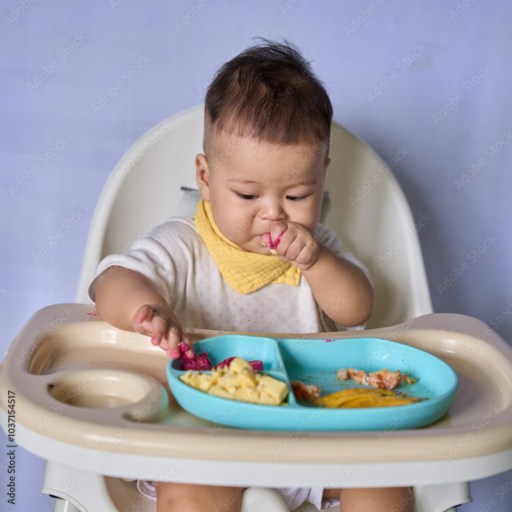 9 month old Asian baby boy is learning to eat, with food on the table, the baby eats and commands himself, it seems a bit messy 9 month old Asian baby boy is learning to eat, with food on the table, the baby eats and commands himself, it seems a bit messy