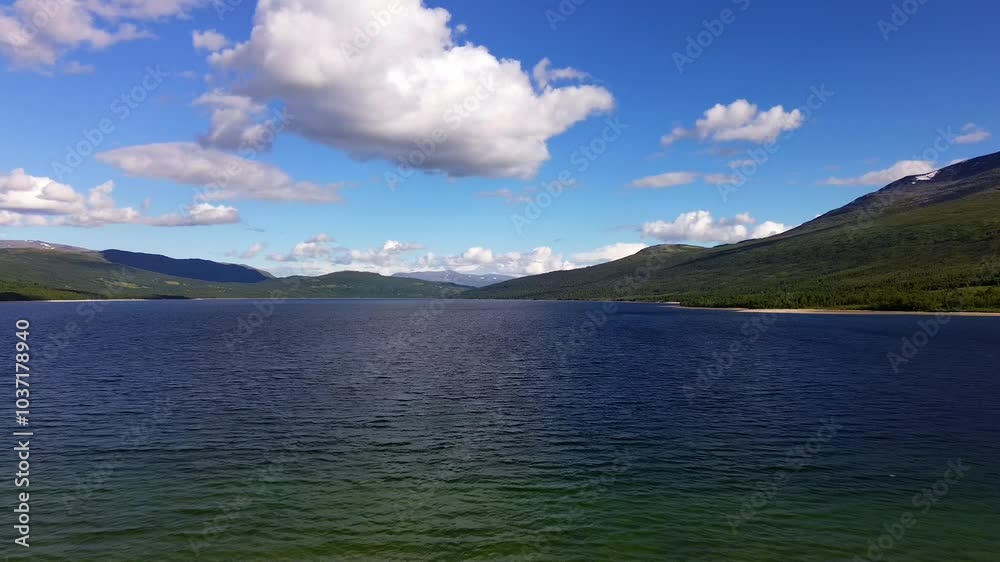 A breathtaking 4k aerial video captures a serene blue mountain lake nestled amidst lush green mountains in Norway. A breathtaking 4k aerial video captures a serene blue mountain lake nestled amidst lush green mountains in Norway.