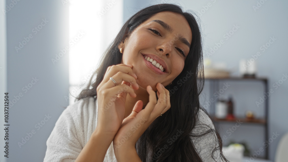 Woman smiling in a spa room, capturing a relaxed and content vibe with her hands gently touching her face while surrounded by wellness products and soft lighting. Woman smiling in a spa room, capturing a relaxed and content vibe with her hands gently touching her face while surrounded by wellness products and soft lighting.