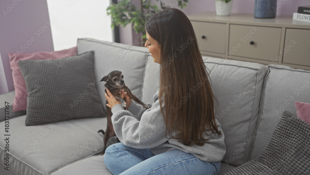 A young woman enjoys quality time with her chihuahua in the cozy living room of her modern apartment
