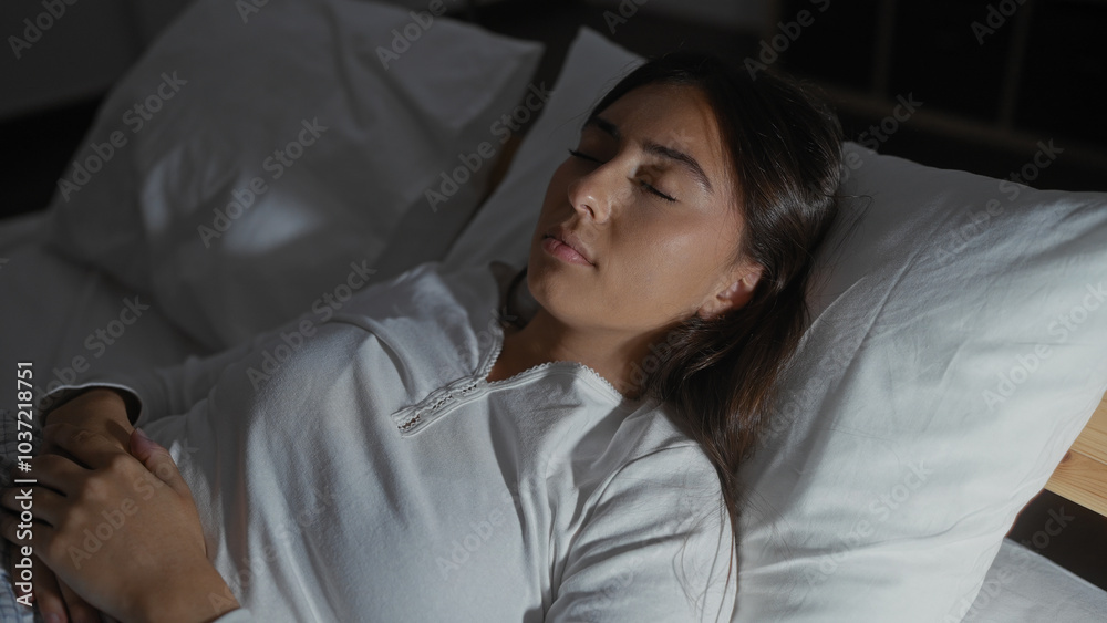 Young woman sleeping peacefully in bed, with brunette hair, wearing white top in bedroom at home, showcasing calm indoor scene of relaxation Young woman sleeping peacefully in bed, with brunette hair, wearing white top in bedroom at home, showcasing calm indoor scene of relaxation