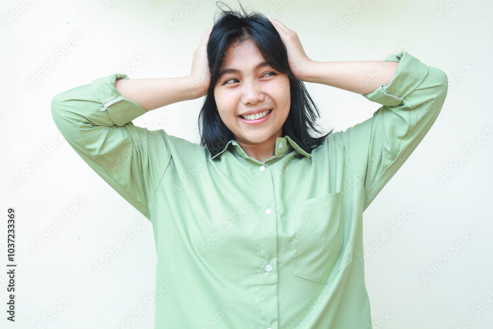 no way. smiling asian woman wearing green over size shirt grabbing her head and looking away see something unbeliavable while standing over isolated white background no way. smiling asian woman wearing green over size shirt grabbing her head and looking away see something unbeliavable while standing over isolated white background