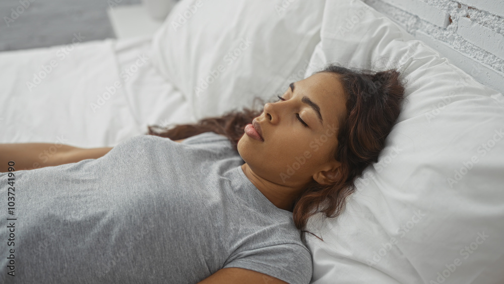 Obraz premium Young woman sleeping peacefully in bed with white bedding in a bright bedroom.