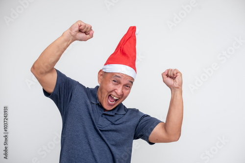 Cheerful middle-aged man celebrating Christmas with Santa hat and raised arms photo