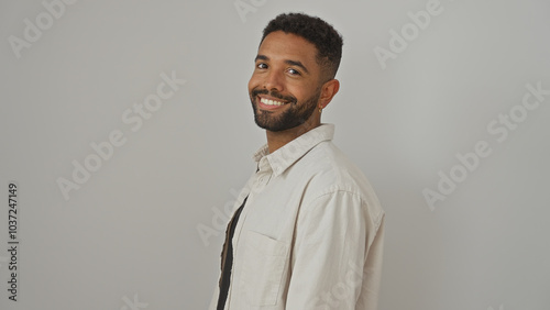 Smiling young adult black man with beard in casual shirt standing against a white background